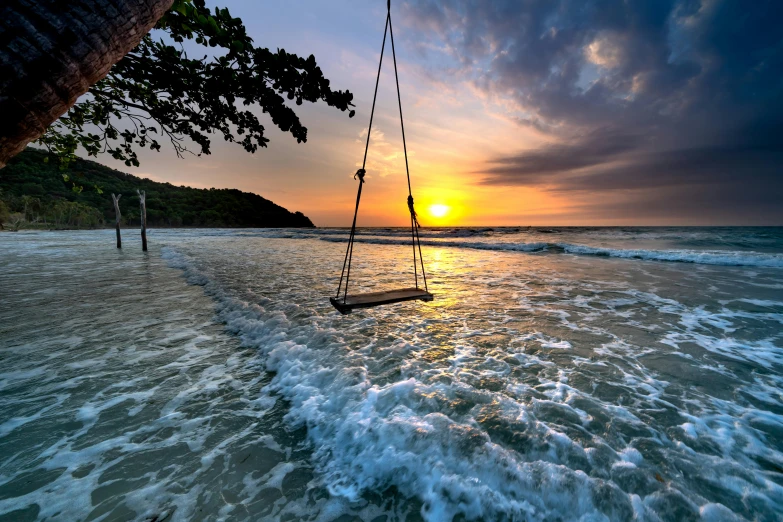 a sunset over the ocean with waves crashing