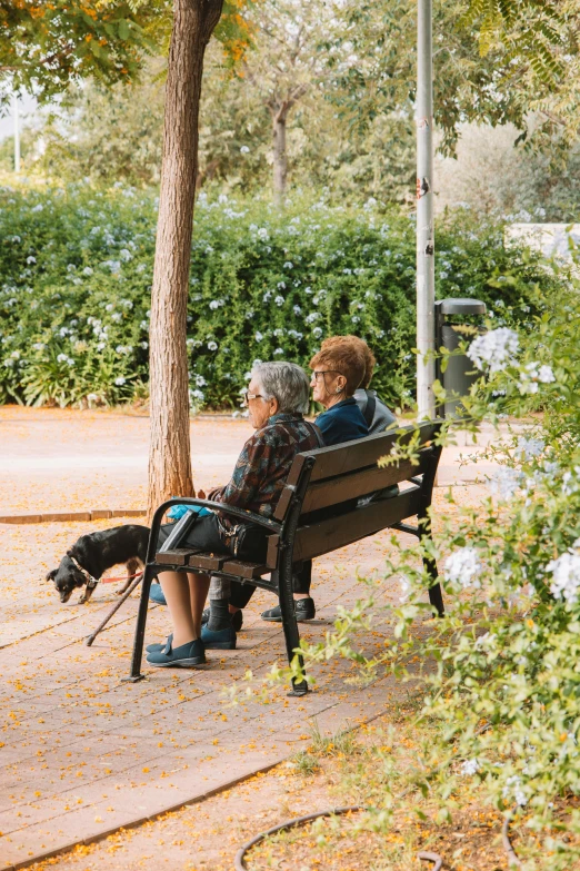 two older women are sitting on an empty bench