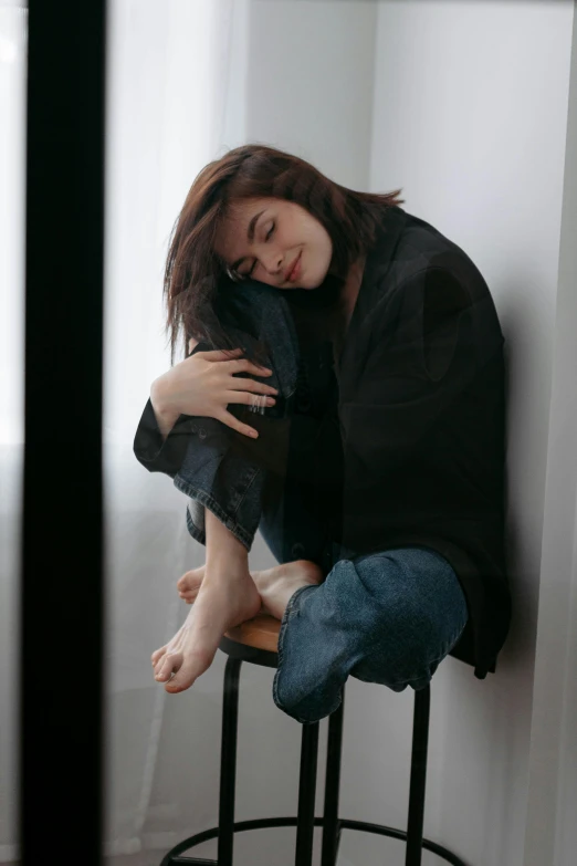 a person sitting on a stool holding onto a stuffed animal