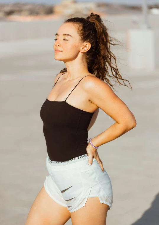 a woman in white shorts and black shirt standing near the ocean