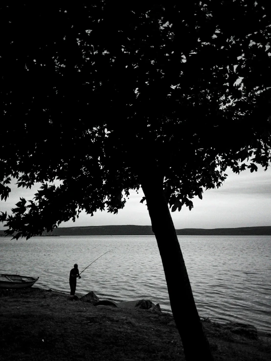 a black and white po of two people fishing from the shore