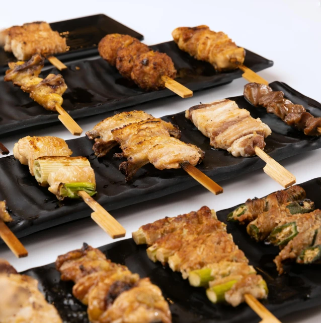 grilled food items on black serving trays on a table