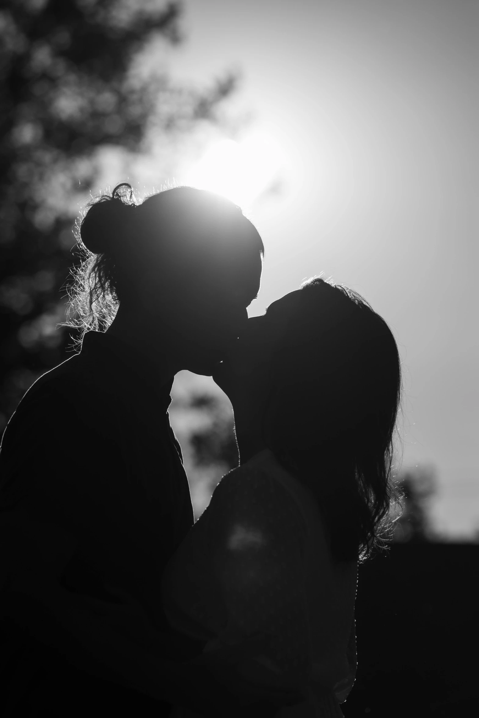 two people kissing each other near trees