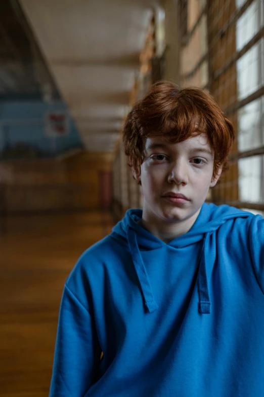 a boy in a blue hoodie is staring at the camera