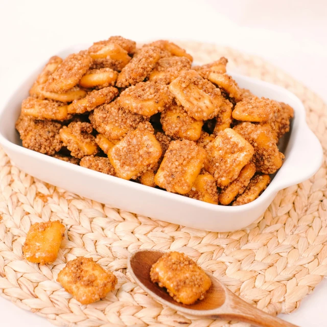 a bowl of fried donuts on a straw mat and wooden spoon