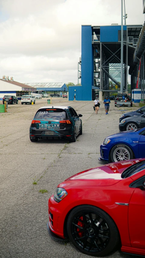 several cars parked on a lot with a building in the background