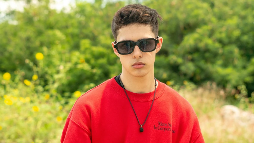 a young man in glasses stands outside