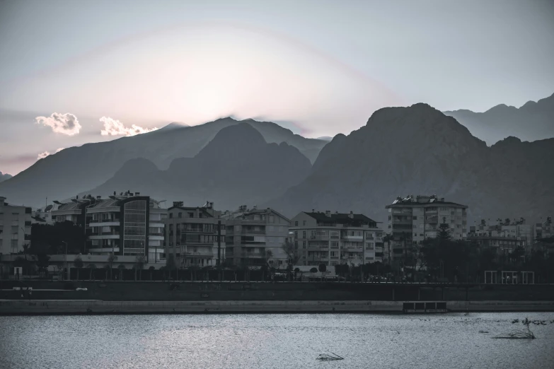 a view of a town, mountains, and river from across the water