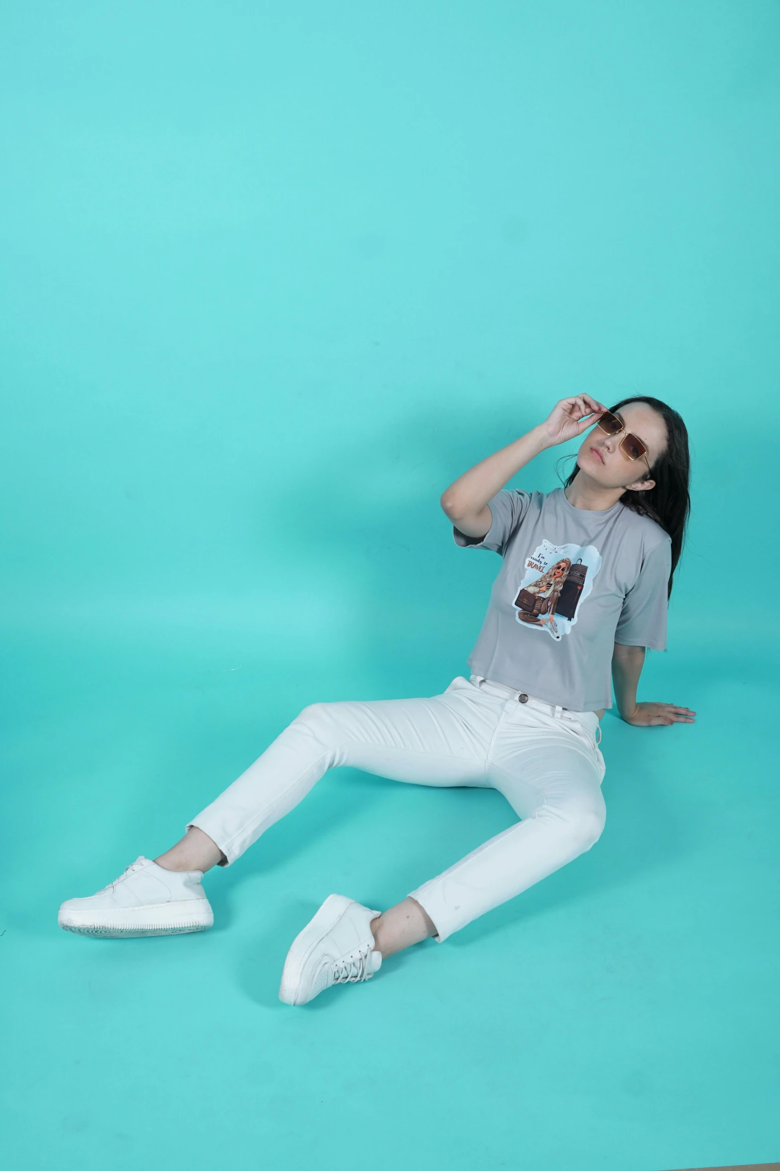 the girl is laying down in white pants and shades