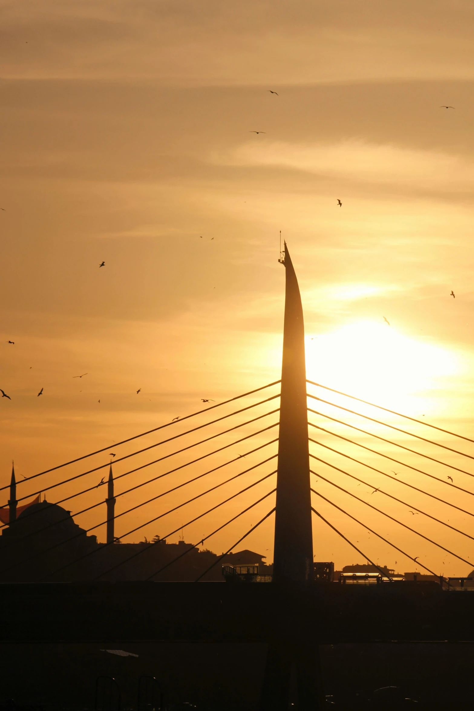 birds are flying near a tall structure with a sunset in the background