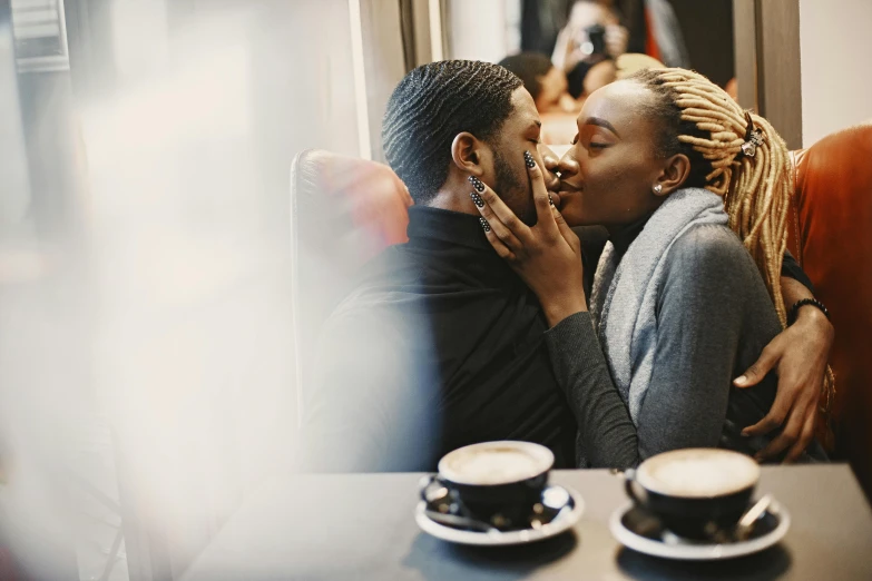 a couple kisses while sitting at a table in a cafe