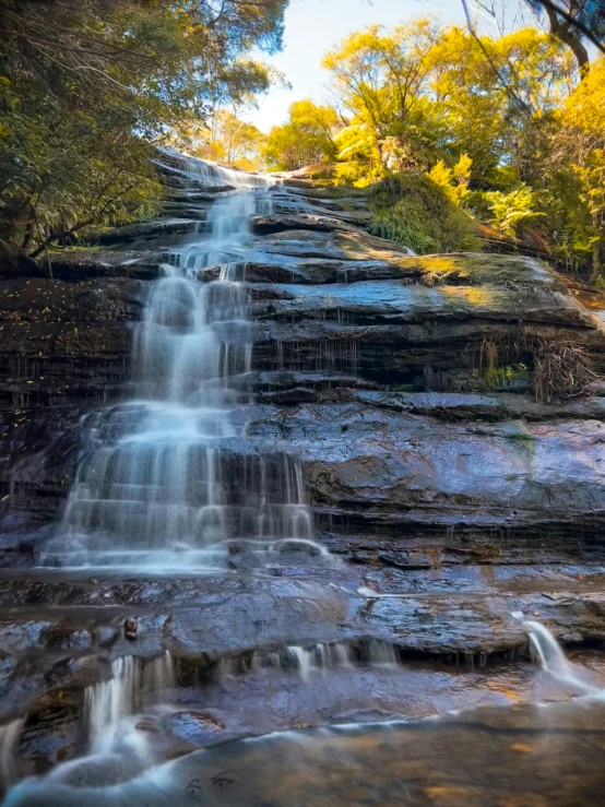 a large waterfall next to lush trees and water