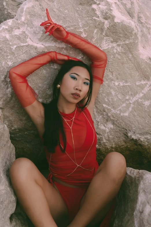 a woman wearing a red body suit on top of a rock