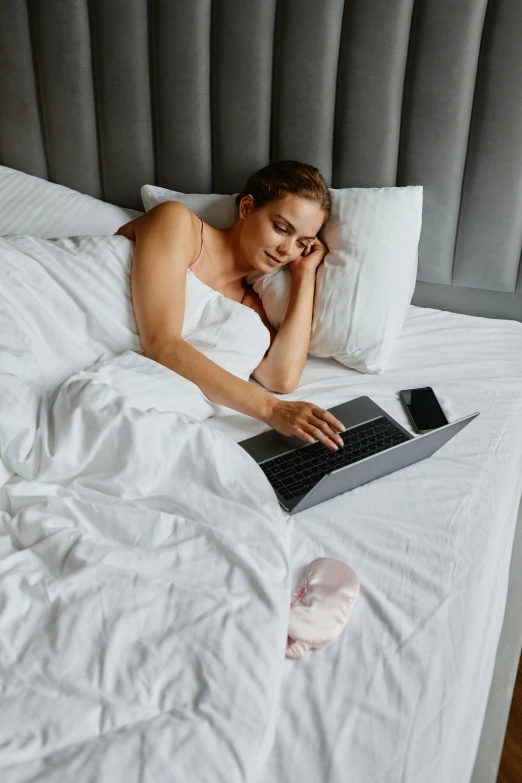 a young woman on her bed looking at a laptop