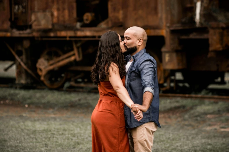 an engaged couple stands together near train tracks