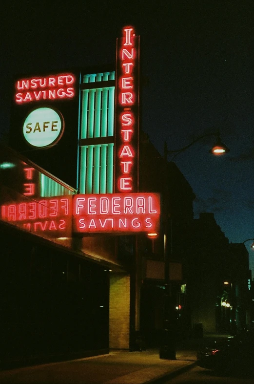 a neon sign in front of a building with a round clock at the top