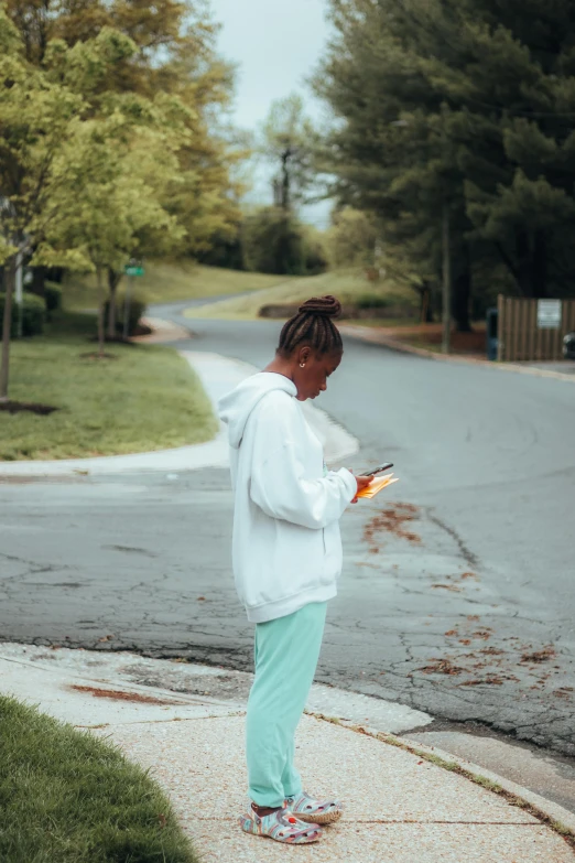 the person is standing at an intersection looking at his cell phone