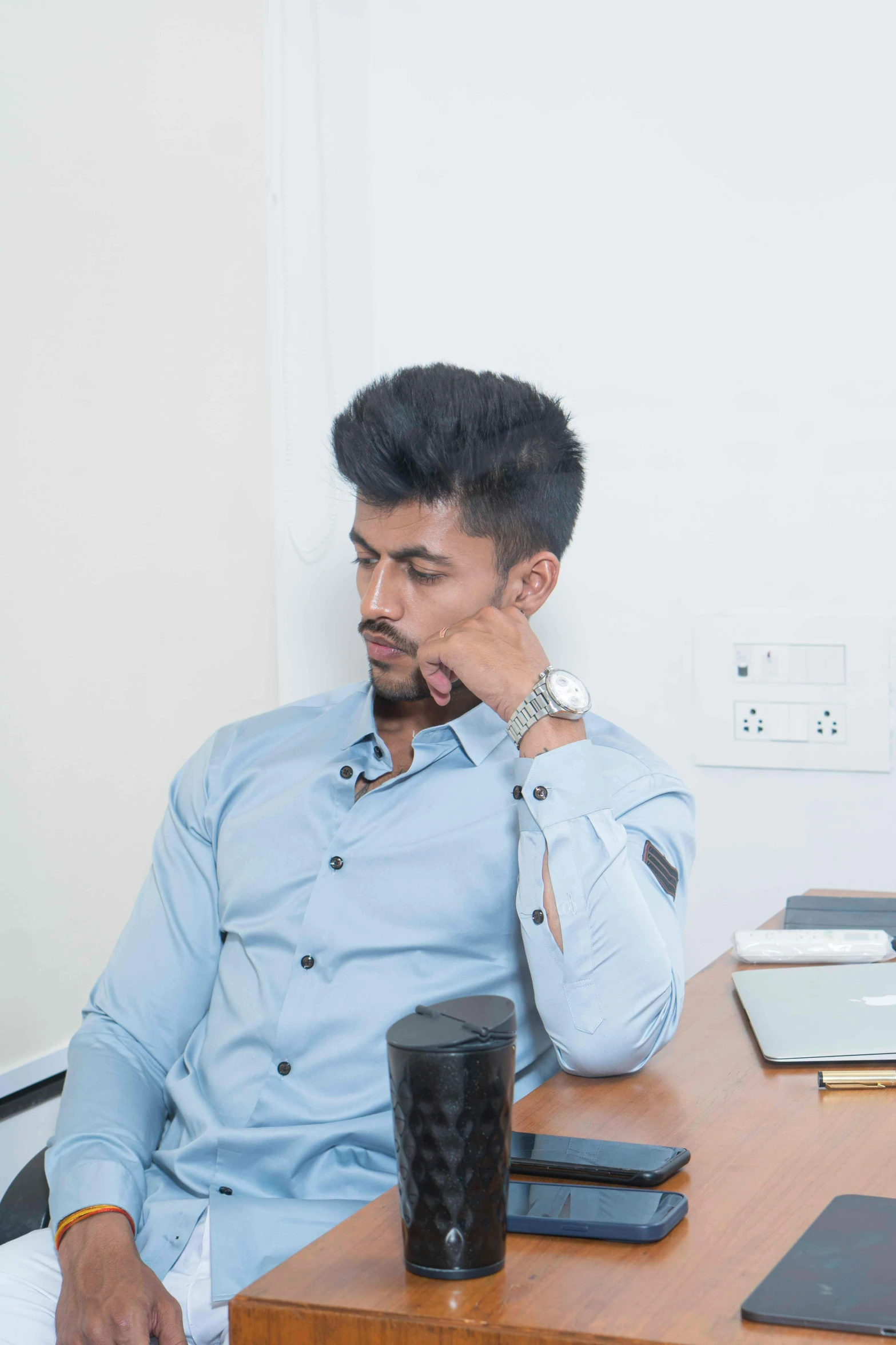 a man wearing a blue on up shirt and talking on the phone