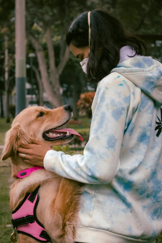 there is a woman standing with her dog in the park