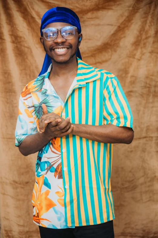 a man standing in front of a curtain wearing a green and yellow shirt