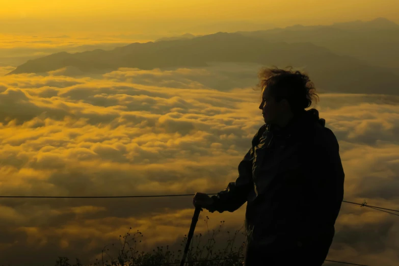 a person with ski poles standing in front of some clouds