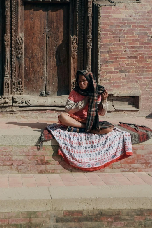 a woman sitting on the ground with her hand in her pocket