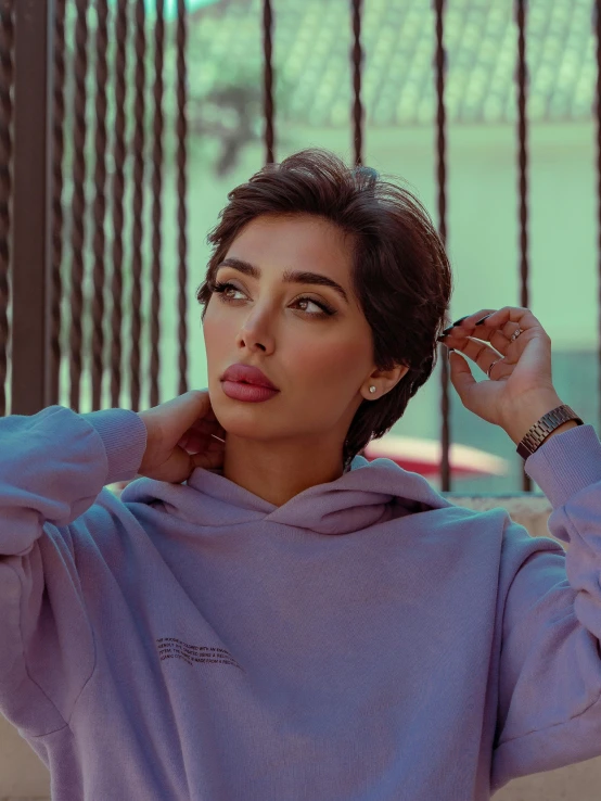 a woman wearing a blue sweater stands near a fence