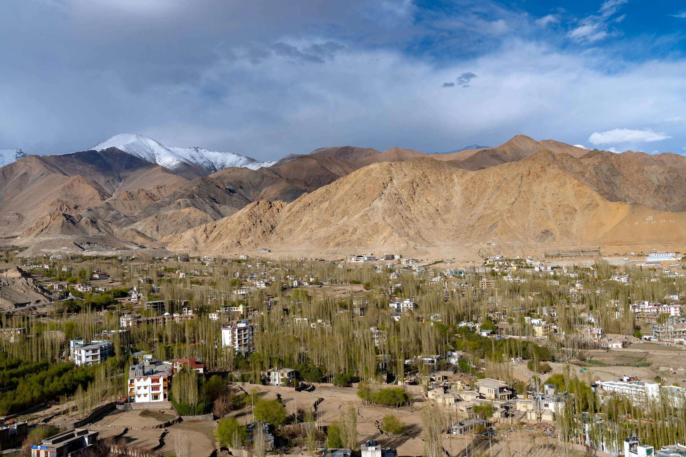 a town surrounded by trees and mountains under a cloudy sky