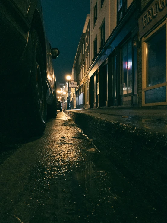 a narrow street has rain on the ground at night