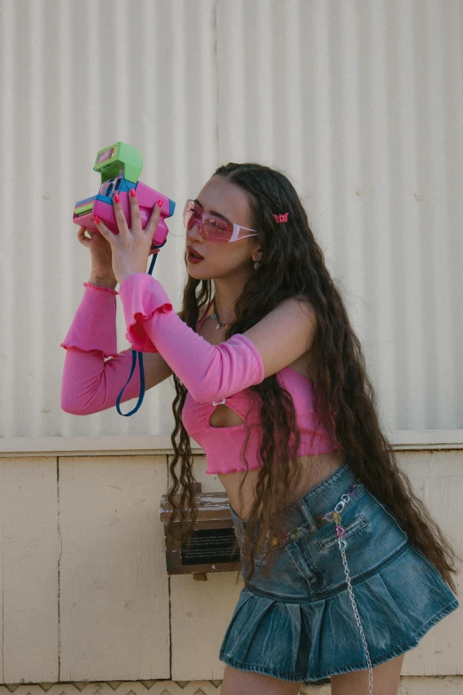 a girl wearing pink is holding up a toy