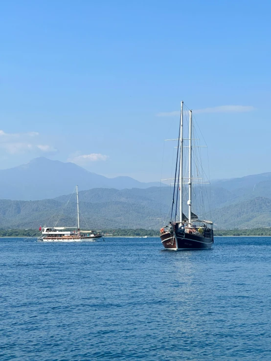 two large boats sitting on top of a lake next to each other