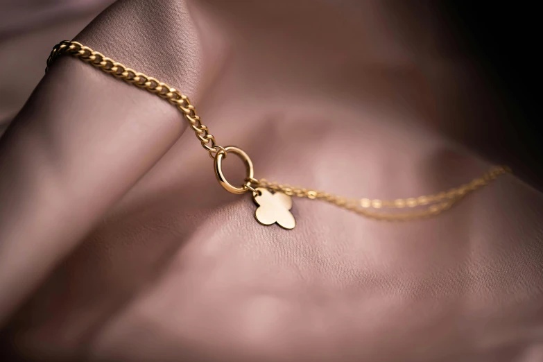 a gold necklace with a heart shaped disc and a cross charm on it