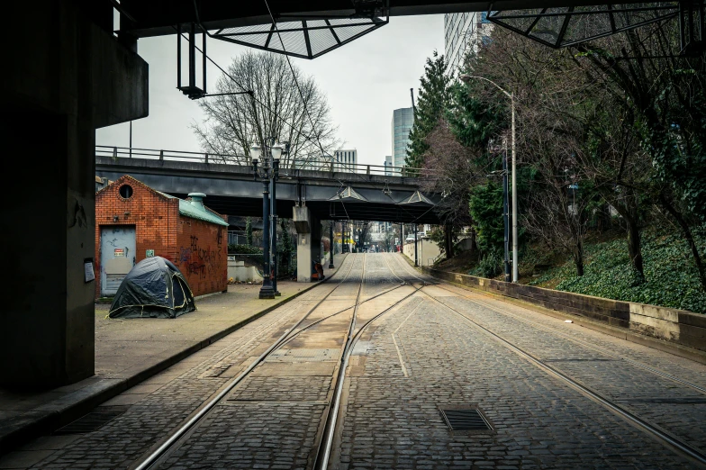 a city street is deserted at night with tracks down