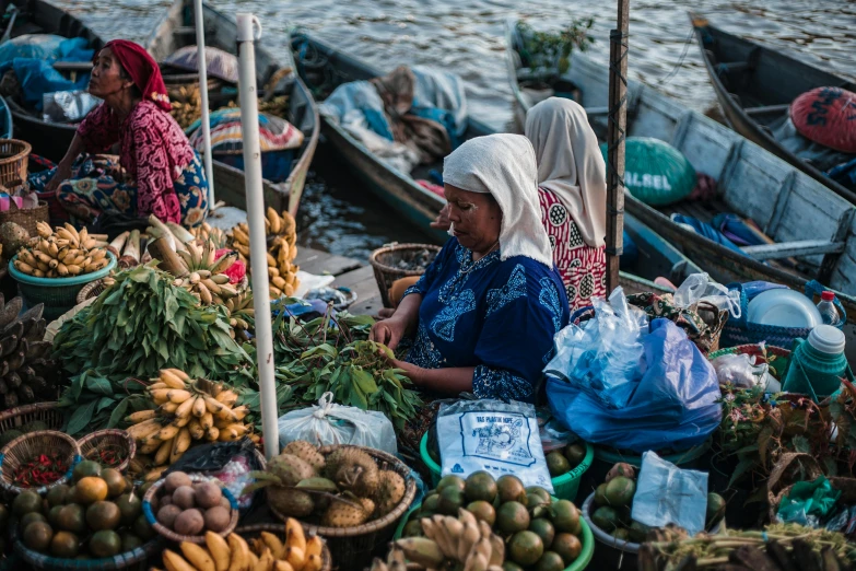 people sitting on boats at an outdoor market