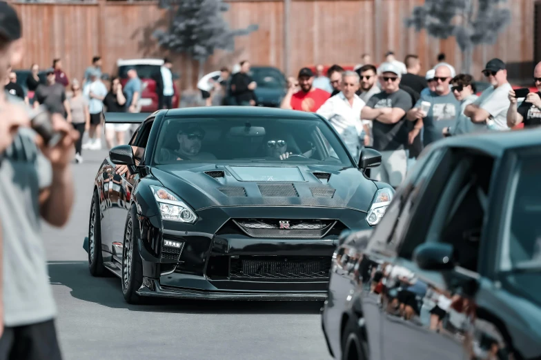 a black car driving past a crowd of people