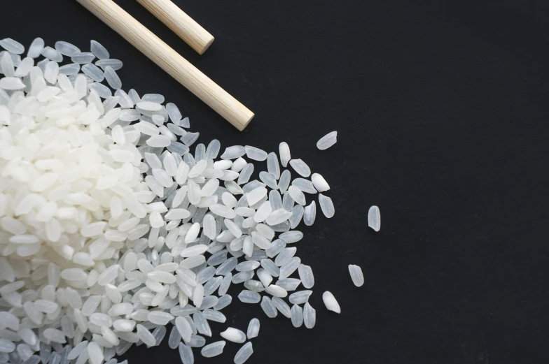 some white rice are on the table next to chopsticks