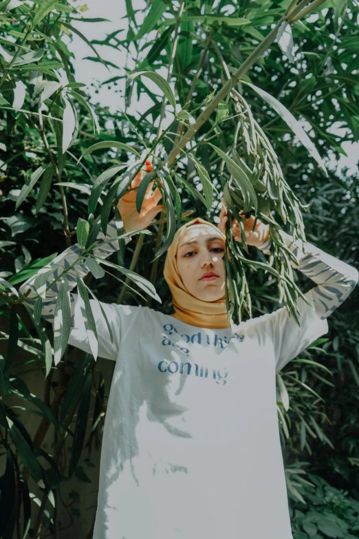 a young woman standing underneath a tree wearing a scarf