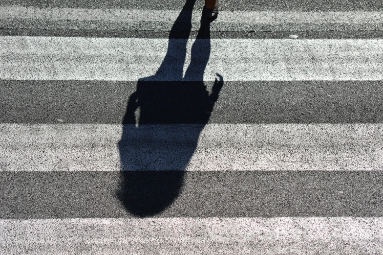 two people crossing a street with shadows on the road