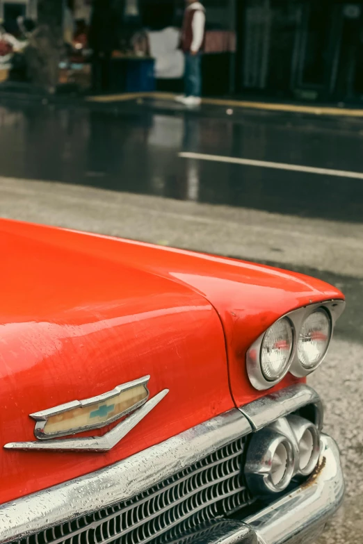 the front end of an old red car with two lamps