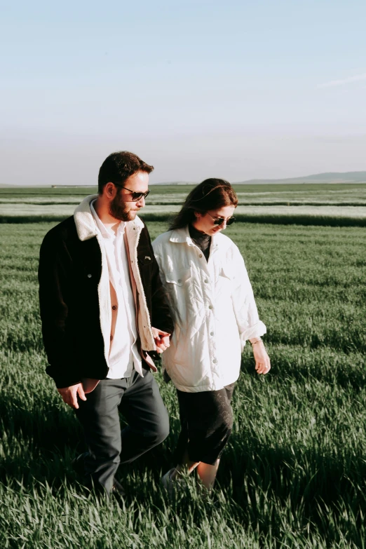 a man and woman walking through a field together