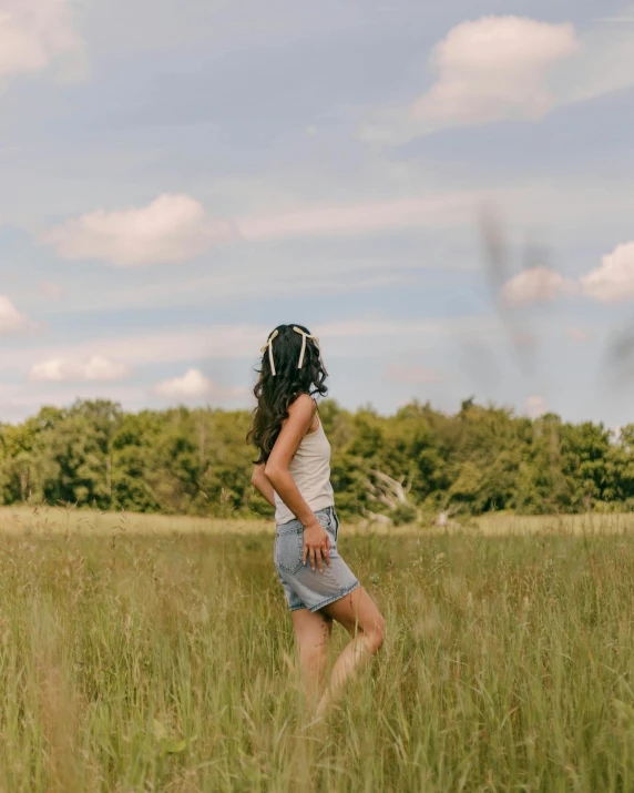 a girl is walking through the grass in the field