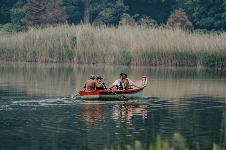 three people are in a small red boat