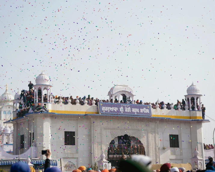 people flying kites in front of a temple with confetti everywhere