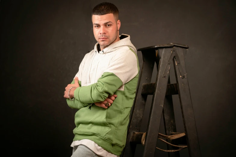 a young man sitting with his arms folded on a bench