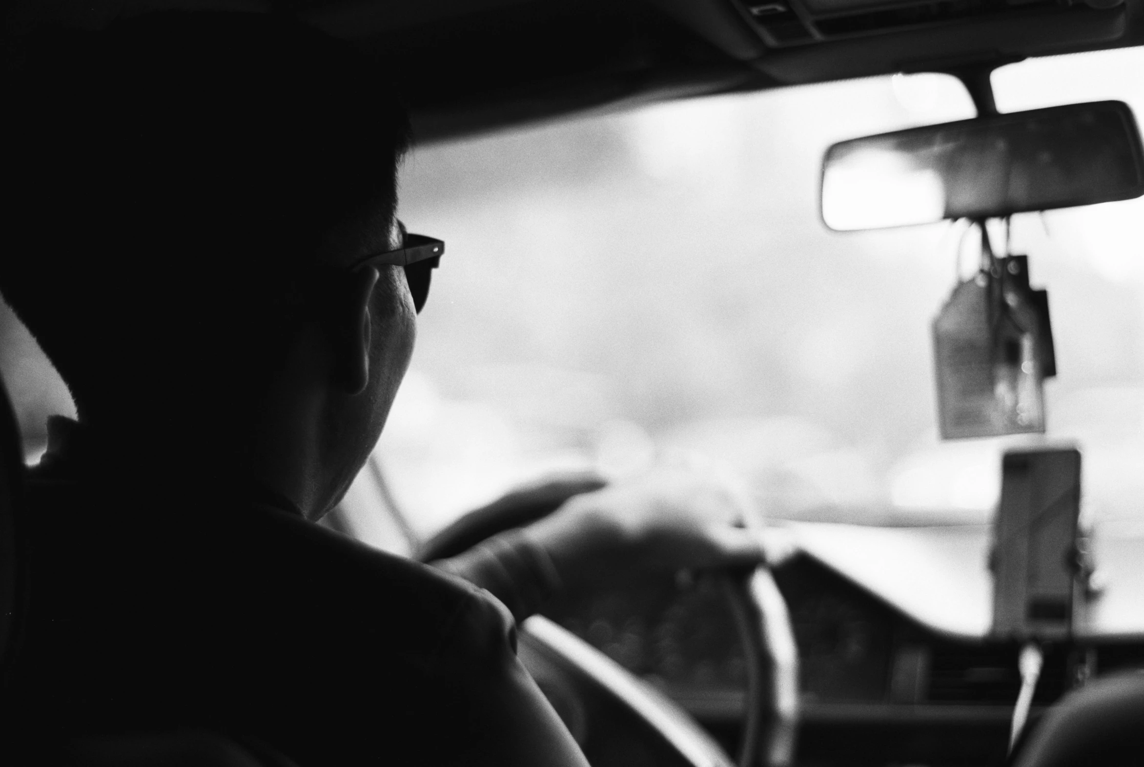 a man driving a car wearing glasses in the back seat