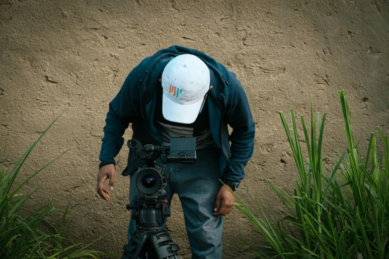 a person wearing a hat with the camera attached and some grass and sand