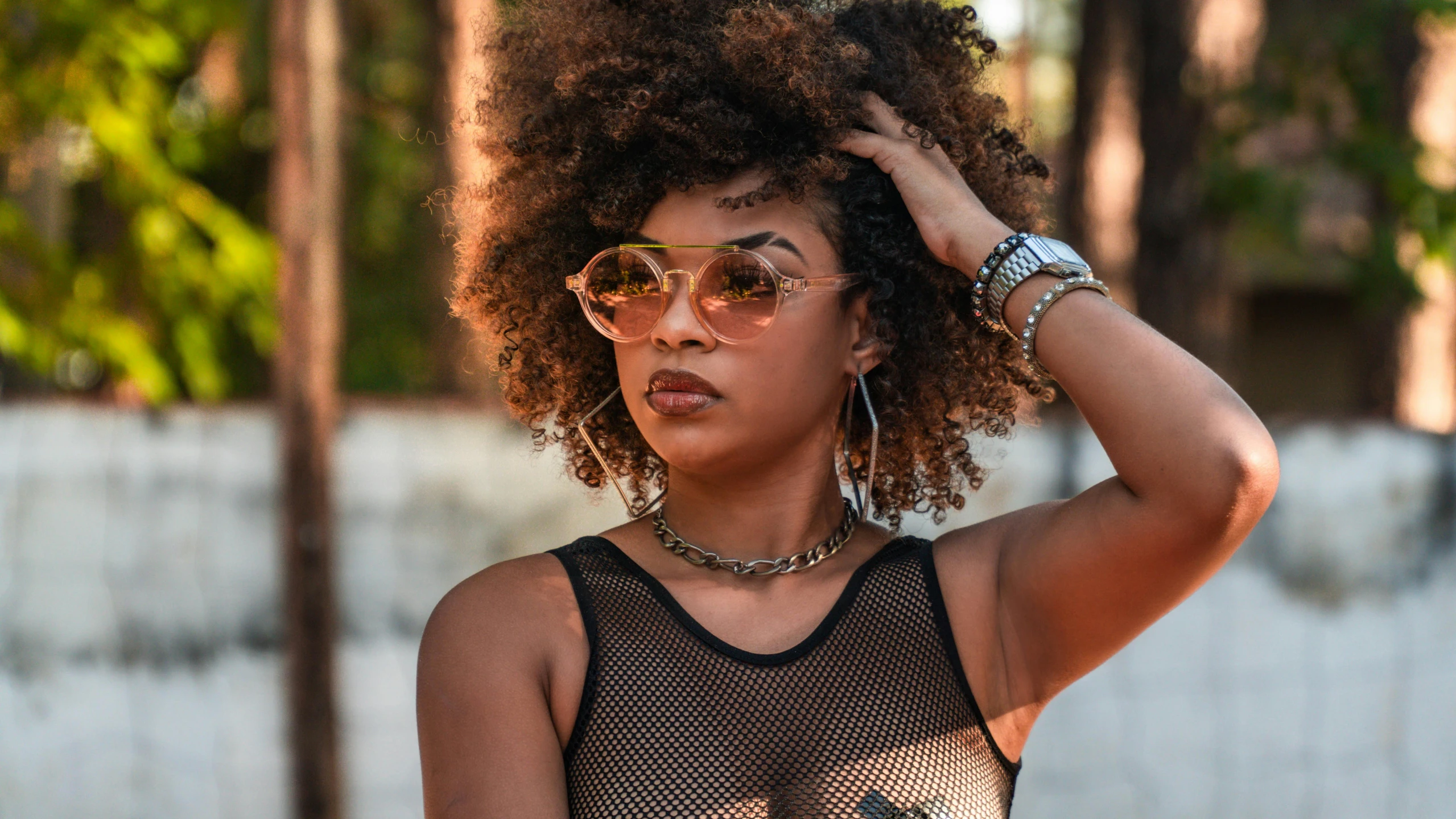 a woman wearing a black tank top, sunglasses, and metal celets