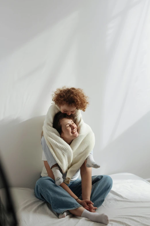 a man and woman sitting on a bed with a blanket