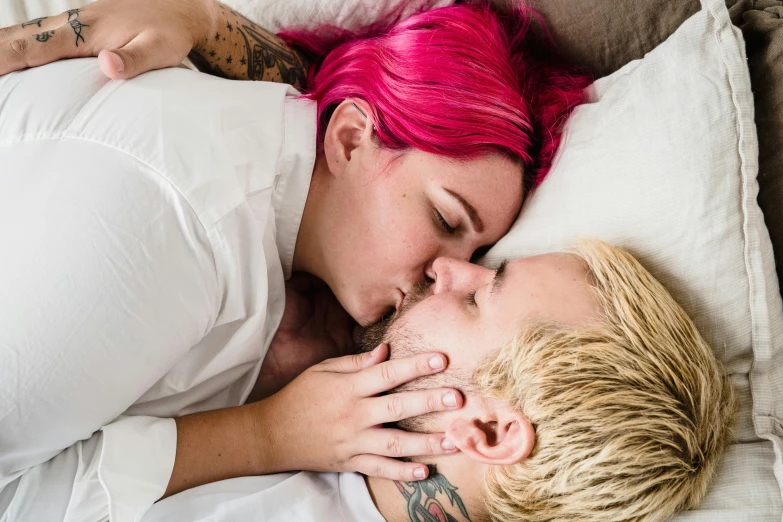 two people laying down and one is kissing another