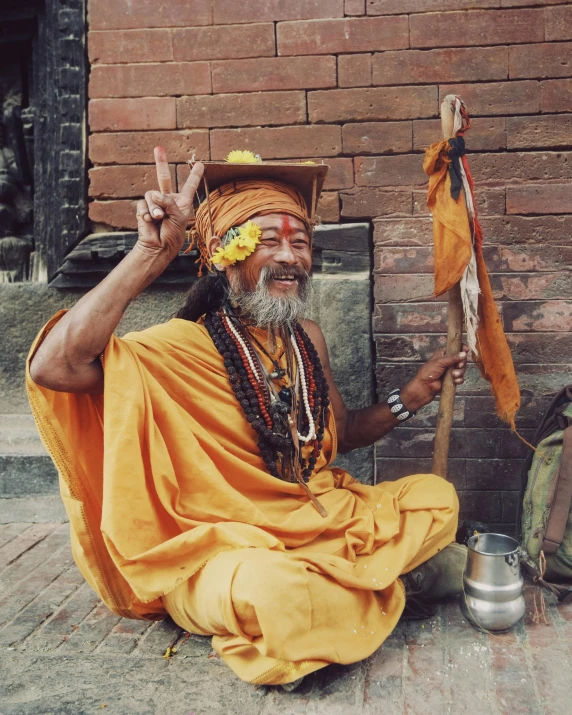 an elderly man dressed in orange sitting on a step